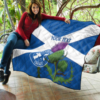 Person holding blue and white quilt with Scotland Cricket emblem and purple thistle artwork.