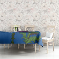 Blue tablecloth with green floral design on table with light chairs