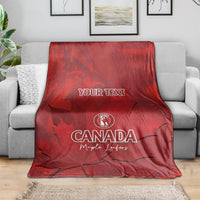 Red Canada cricket blanket folded over sofa, YOUR TEXT center with maple leaf print
