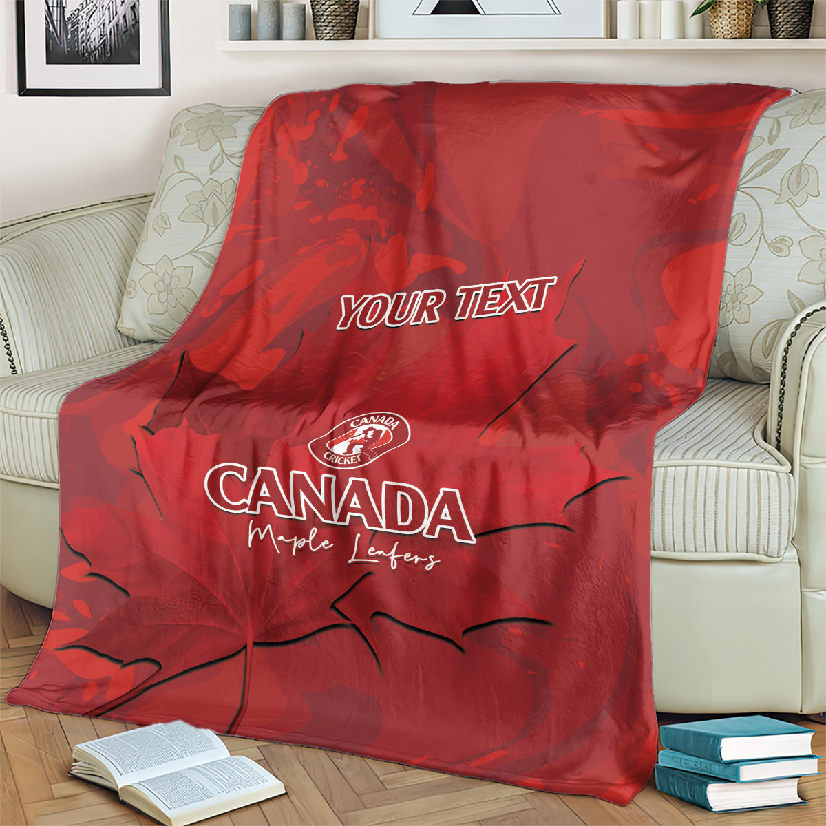 Red Canada cricket blanket over cushioned sofa, YOUR TEXT and maple leaf artwork