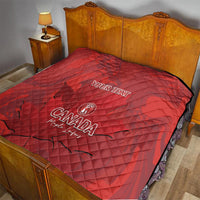Red quilt blanket with custom text and Canada logo over bed, quilted diamond pattern