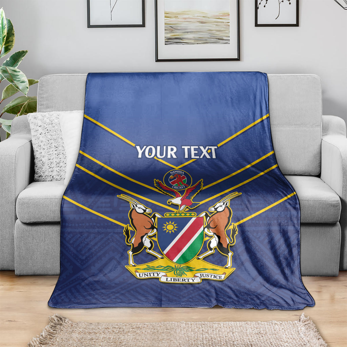 Blue cricket blanket with yellow stripes and 'YOUR TEXT' crest, over a sofa.