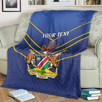 Blue cricket blanket with yellow lines and 'YOUR TEXT' crest on a couch.