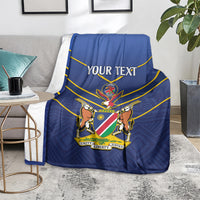 Blue cricket blanket with yellow stripes and 'YOUR TEXT' crest on a gray sofa.