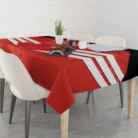 Red tablecloth covering dining table with white stripe pattern and folded corners.