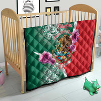 Quilt draped on a baby bed in green and red with eagle and purple flower designs.