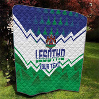 Personalised quilt laid on lawn with blue top, white center, green bottom and crest
