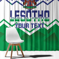 Close-up Lesotho-themed window curtain with green zigzags, blue text, and crest at top.