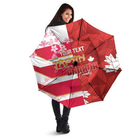Red custom umbrella with Canada flag stripes and cherry blossom detail, held open