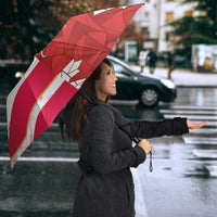 Red custom umbrella with geometric maple leaf and striped Canada design, in rain