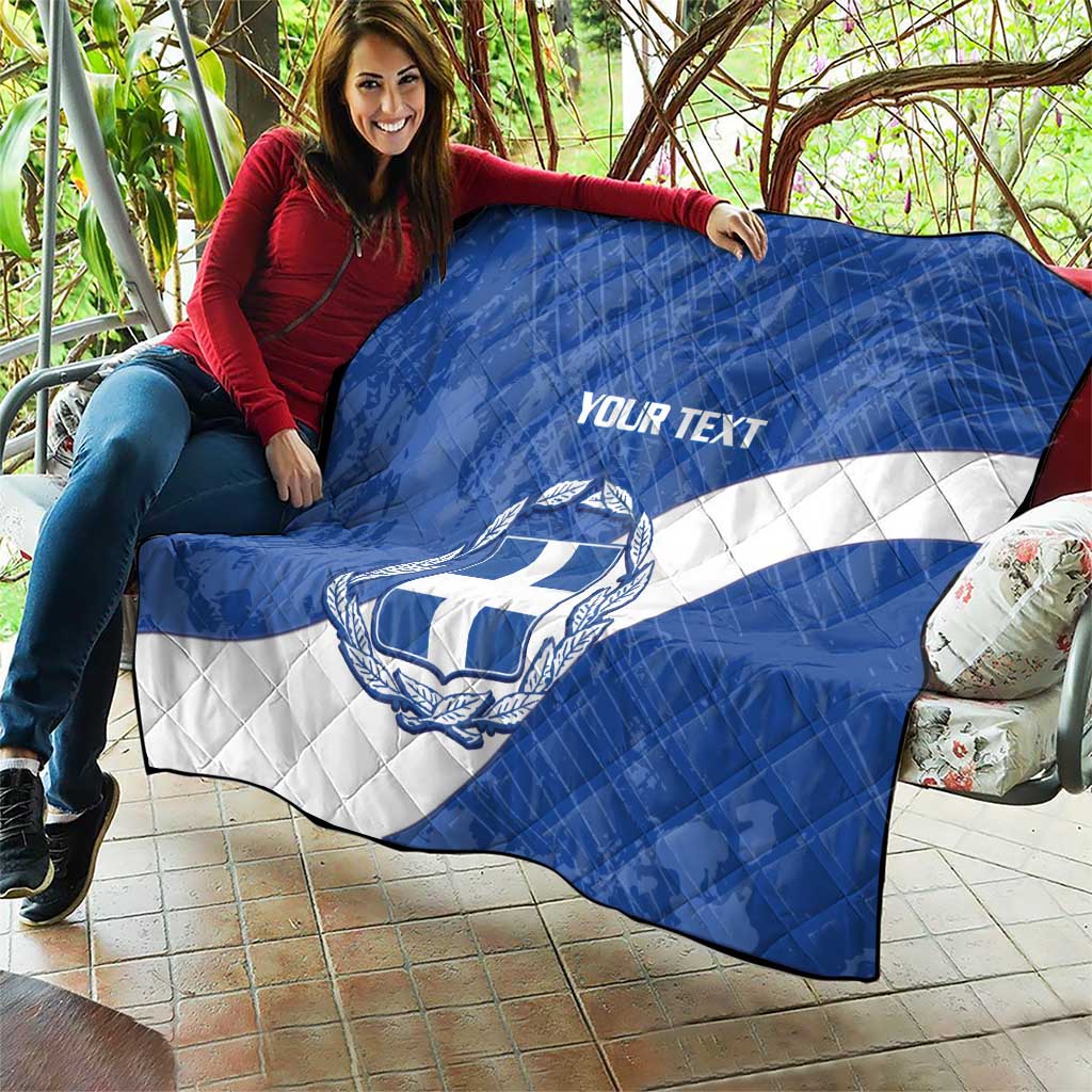 Blue and white Greece quilt draped over outdoor sofa, crest and 'YOUR TEXT' visible