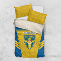 Blue-and-yellow bedding set with Sweden crest and custom text on duvet, two yellow pillows.
