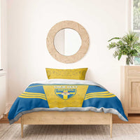 Blue-and-yellow bedding set with Sweden crest and custom text on duvet, two yellow pillows.