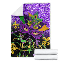 Purple Mardi Gras blanket folded with glitter top, ornate mask art, and peacock feather accents