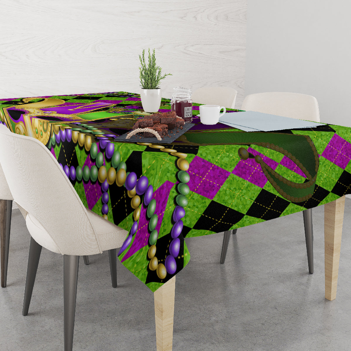 Colorful Mardi Gras tablecloth draped on a dining table, jester mask and bead pattern in green/purple