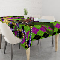Colorful Mardi Gras tablecloth draped on a dining table, jester mask and bead pattern in green/purple