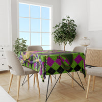 Colorful Mardi Gras tablecloth on dining table with jester mask, green/purple bead border, diamond details