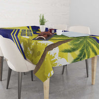 Blue and yellow tablecloth with green palm leaves, draped over square dining table