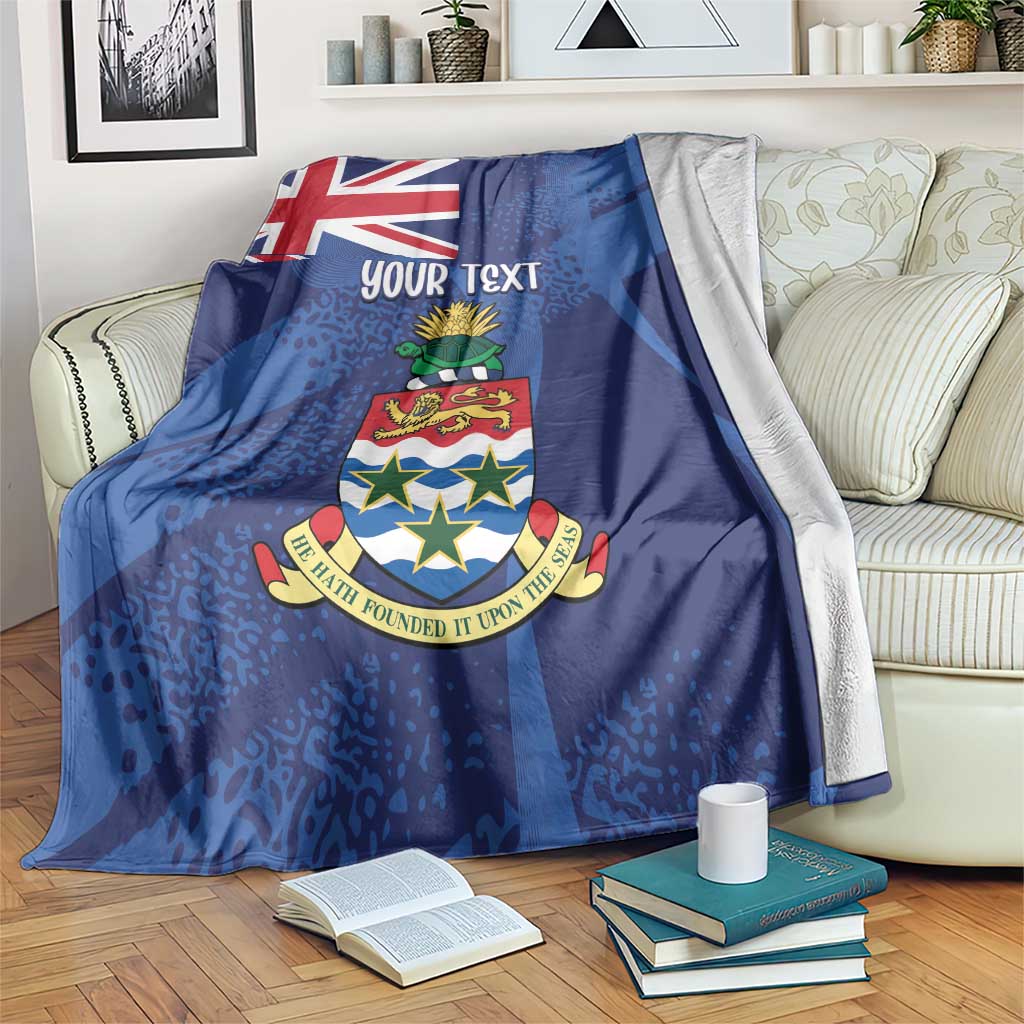 Blue blanket throw with Union Jack, crest, and 'YOUR TEXT' on a lounge sofa.