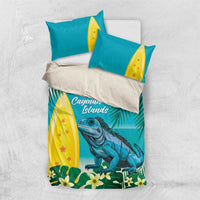 Turquoise bedding set flat lay: duvet and pillows with iguana, palms, and yellow surfboards