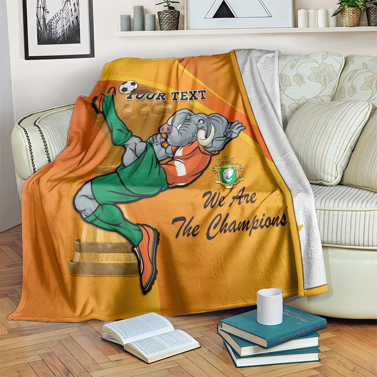 Orange football blanket draped with mascot lifting trophy, 'YOUR TEXT' and 'We Are The Champions'