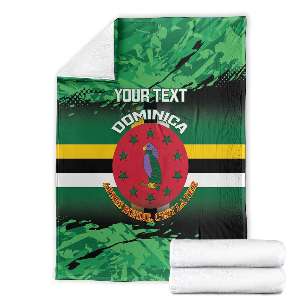 Green printed throw blanket with Dominica crest, stripes, and 'YOUR TEXT', neatly folded