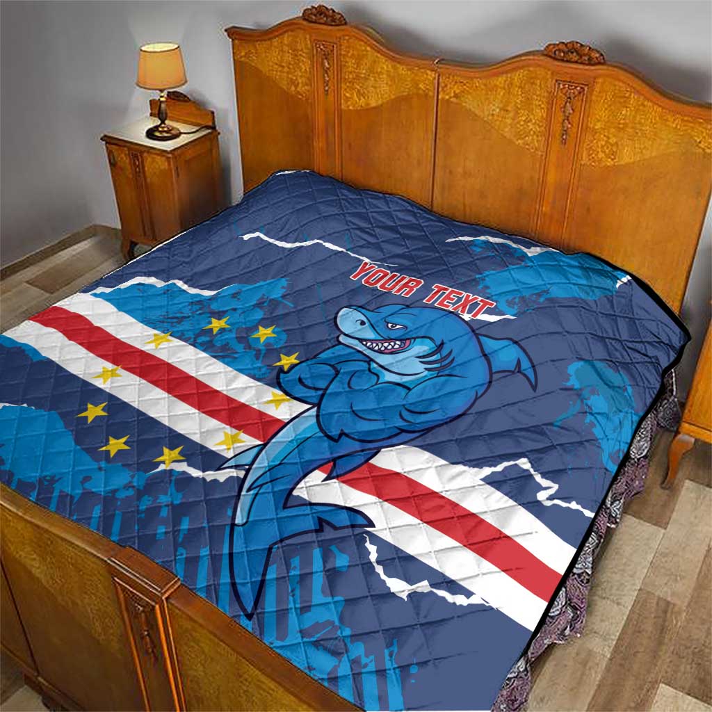 Blue quilt blanket on bed with shark mascot artwork, stars and stripes, and “Your text”