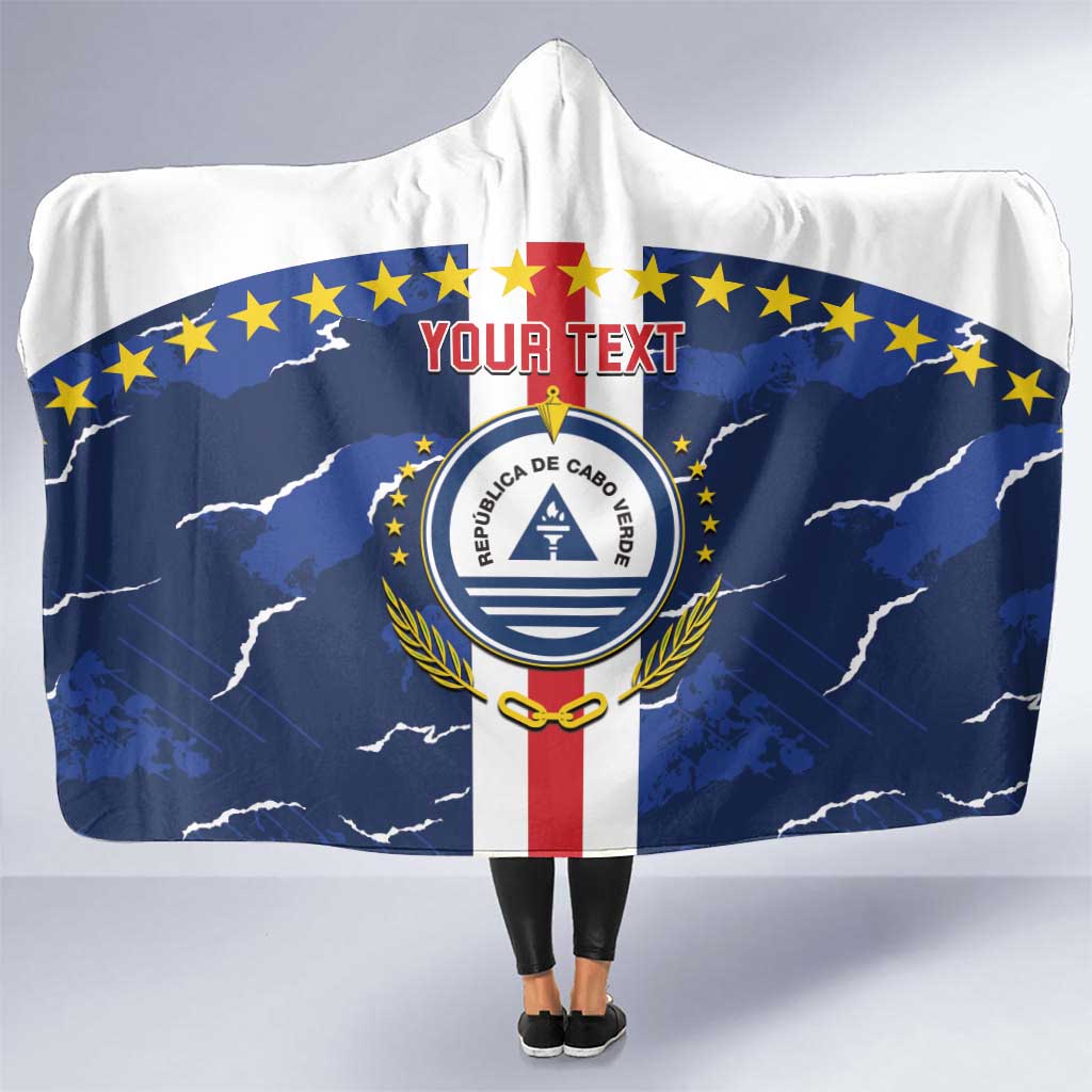 Hooded blanket cape, white with blue crest, star border, and front hood.