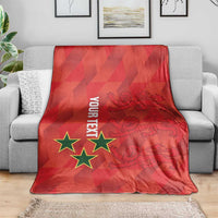 Red football blanket with star and crest graphic, folded over a gray couch