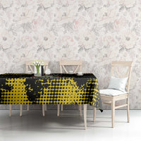 Black and yellow speckled tablecloth on long dining table with chairs