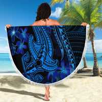 Blue round beach blanket with white fringe; tribal shark and floral motif held up on sand