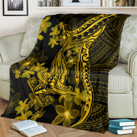 Black blanket draped on couch with gold Polynesian shark and plumeria artwork