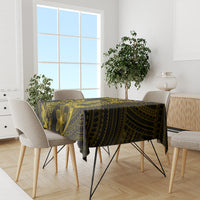Dark tablecloth with gold Polynesian geometric and floral motifs across dining table