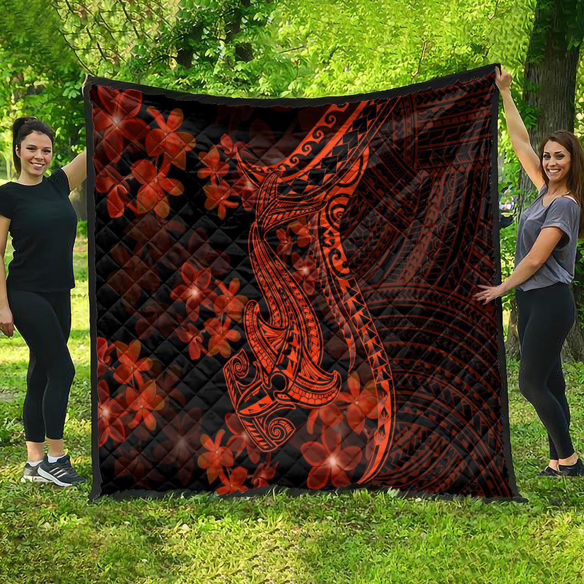 Quilt blanket spread outdoors: black with orange tribal shark tattoo and red flowers