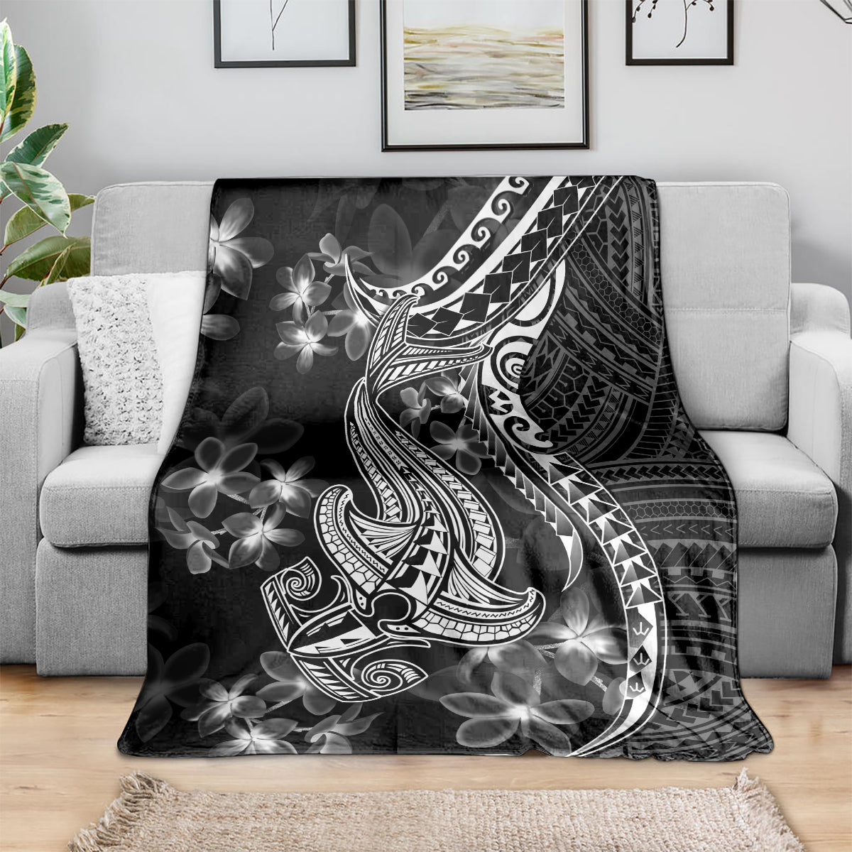 Black blanket draped over couch, featuring white shark tattoo and Polynesian floral design