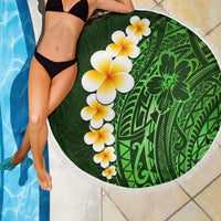 Green round beach blanket with white fringe, plumeria flowers and tribal leaf design.