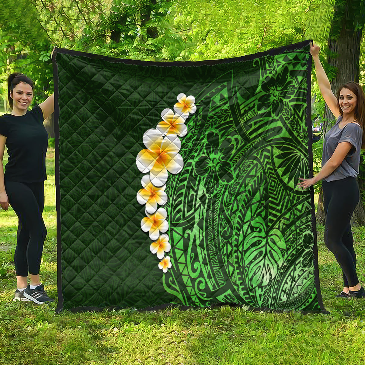 Green quilted blanket held outdoors, featuring bold green leaf and plumeria flower design.
