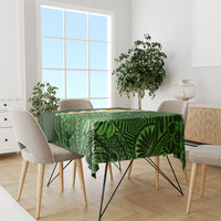 Green tropical tablecloth with leaf motifs and plumeria flowers on dining table