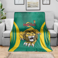 Green football blanket on couch with yellow curved stripes, lion face graphic, Your Text
