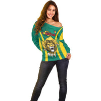 Green off-shoulder sweater with yellow stripes and large lion crest graphic center.