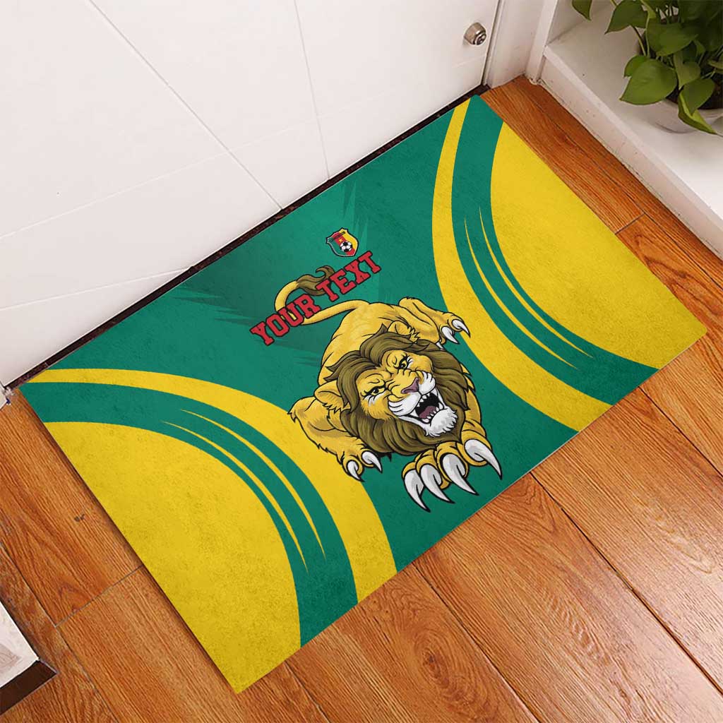 Green rubber doormat with lion head, curved yellow stripes, and 'YOUR TEXT' near entry
