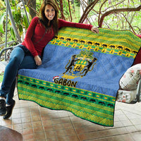 Blue quilt blanket held on patio, showing Gabon coat of arms and green animal stripe border.