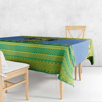 Blue and green holiday tablecloth draped over dining table with Gabon crest motif