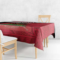 Red Haiti tablecloth with geometric design and emblem banner across the top edge