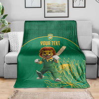 Green cricket blanket on sofa with lion mascot, bat graphic and 'YOUR TEXT'