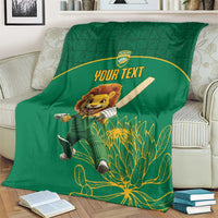 Green cricket blanket on couch with lion mascot, 'YOUR TEXT' and plant motifs