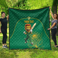 Green quilt blanket spread outdoors, featuring lion mascot in a yellow-bordered custom text circle