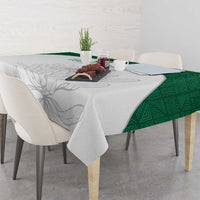 Cricket tablecloth with light gray floral print and green geometric trim at table edge