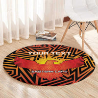 Round orange patterned rug with black zigzags and red-and-yellow eagle over centered text