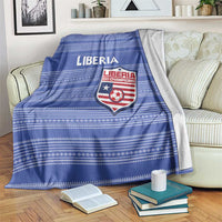 Blue football blanket with Liberia logo and horizontal stripes, draped over sofa